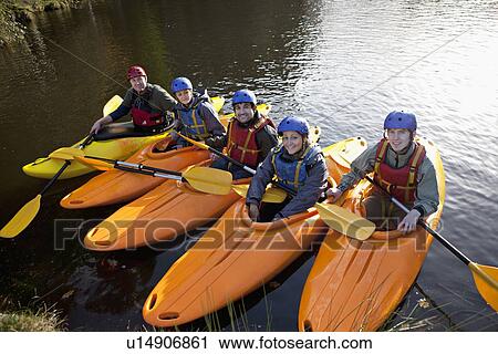 Stock Image - Kayakers lined up in still lake. Fotosearch