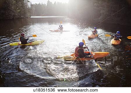 Stock Photograph - Kayakers rowing in still lake. Fotosearch
