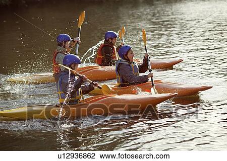 Stock Image - Kayakers rowing together on still lake. Fotosearch