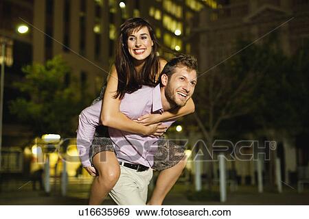 Stock Photo - Man carrying girlfriend on city street. Fotosearch
