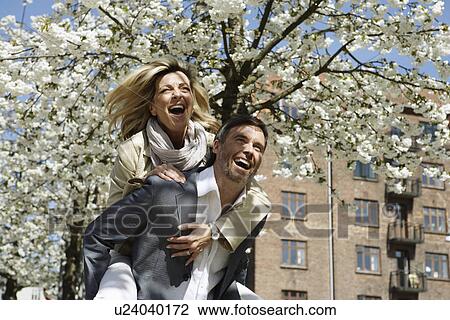 Stock Image - Man carrying girlfriend piggyback. Fotosearch