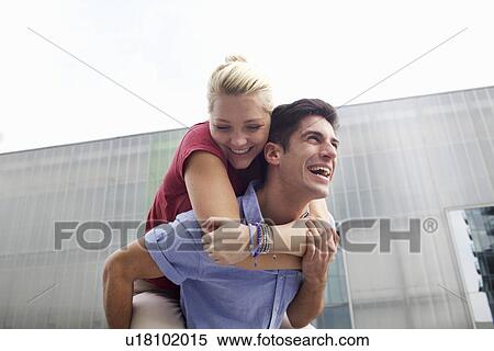 Stock Photography - Man carrying girlfriend piggyback. Fotosearch