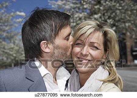 Stock Photography - Man kissing girlfriend outdoors. Fotosearch