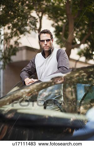 Stock Image - Man leaning on sports car. Fotosearch
