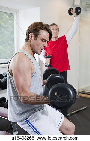 Stock Photo - Man lifting weights in gym. Fotosearch
