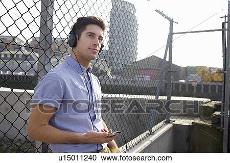 Man listening to headphones on street View Large Photo Image Stock Image - Man listening to headphones on street. Fotosearch