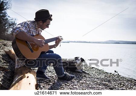 Man playing guitar with dog by creek View Large Photo Image Stock Image - Man playing guitar with dog by creek. Fotosearch