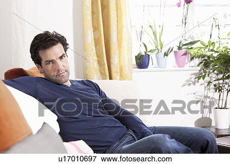 Man relaxing on sofa in living room View Large Photo Image Stock Photo - Man relaxing on sofa in living room. Fotosearch