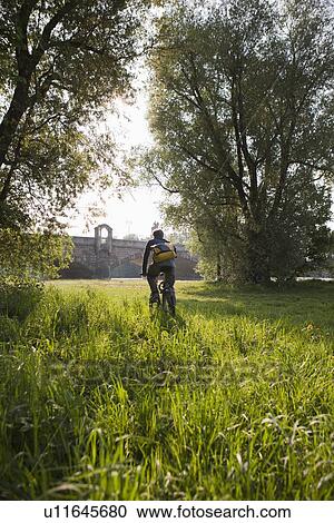 Man riding bicycle in field View Large Photo Image Stock Image - Man riding bicycle in field. Fotosearch