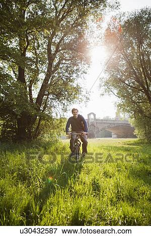 Stock Photo - Man riding bicycle in field. Fotosearch