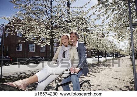 Stock Image - Man riding with girlfriend on bicycle. Fotosearch