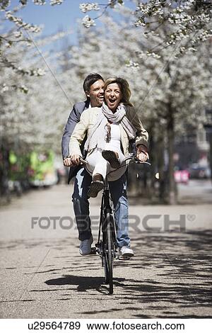Stock Photo - Man riding with girlfriend on bicycle. Fotosearch