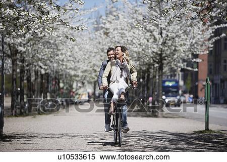Stock Photography - Man riding with girlfriend on bicycle. Fotosearch