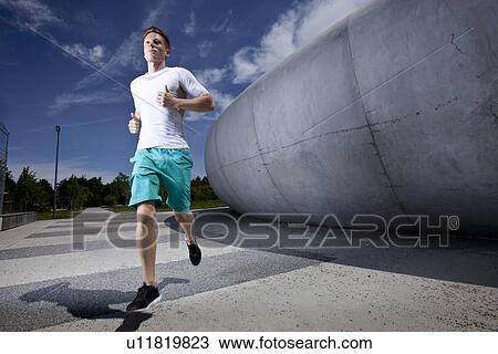 Stock Image - Man running in industrial area. Fotosearch