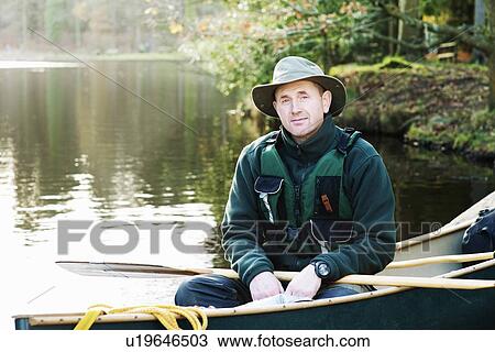 Man sitting in canoe on still lake View Large Photo Image Stock Image - Man sitting in canoe on still lake. Fotosearch