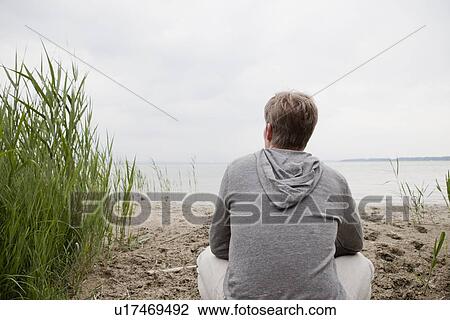Man sitting on sandy beach View Large Photo Image Stock Image - Man sitting on sandy beach. Fotosearch