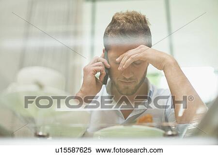 Stock Photography - Man talking on cell phone at breakfast. Fotosearch