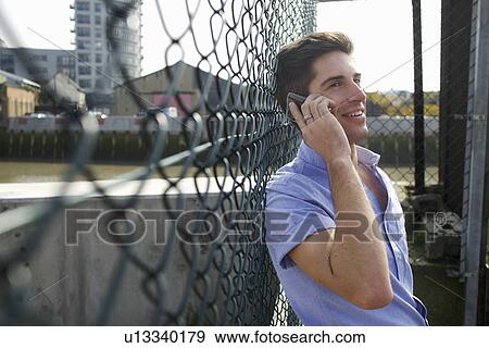 Man talking on cell phone on city street View Large Photo Image Stock Photo - Man talking on cell phone on city street. Fotosearch