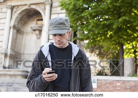 Man using cell phone on city street View Large Photo Image Stock Image - Man using cell phone on city street. Fotosearch