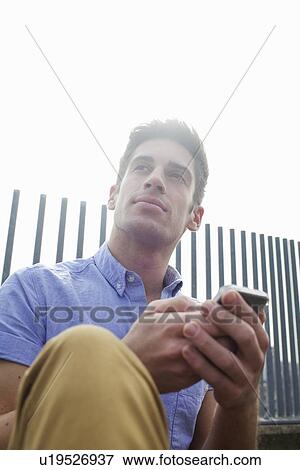 Stock Photo - Man using cell phone on city street. Fotosearch