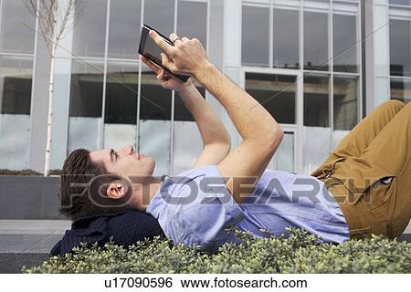 Stock Photograph - Man using tablet computer on city street. Fotosearch