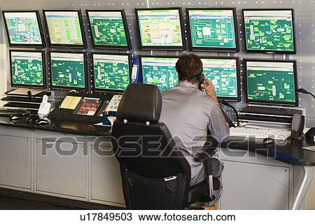 Stock Image - Man working in security control room. Fotosearch