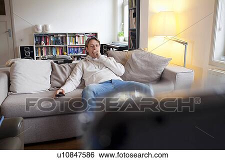 Man yawning in front of television View Large Photo Image Stock Photograph - Man yawning in front of television. Fotosearch