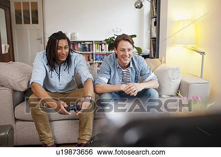 Men playing video games in living room View Large Photo Image Stock Photograph - Men playing video games in living room. Fotosearch