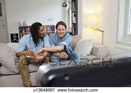 Stock Photo - Men watching television in living room. Fotosearch