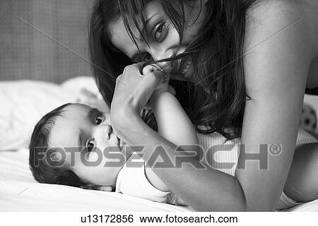 Stock Photograph - Mother and baby laying on bed. Fotosearch