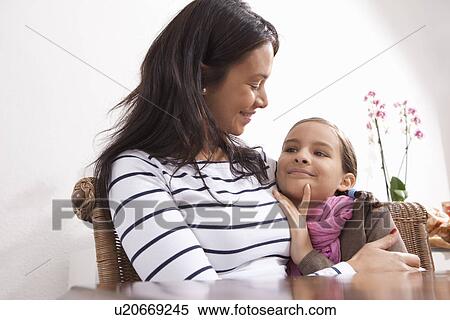 Stock Photography - Mother and daughter hugging at table. Fotosearch