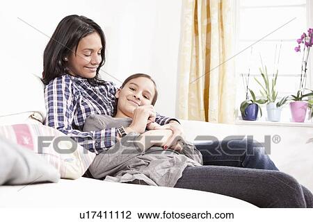 Stock Image - Mother and daughter relaxing on sofa. Fotosearch