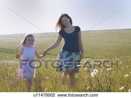 Stock Image - Mother and daughter walking in field. Fotosearch