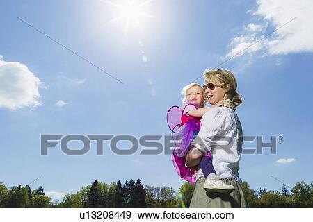 Stock Photo - Mother carrying toddler girl outdoors. Fotosearch