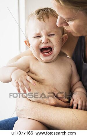 Mother holding crying baby girl View Large Photo Image Stock Photograph - Mother holding crying baby girl. Fotosearch