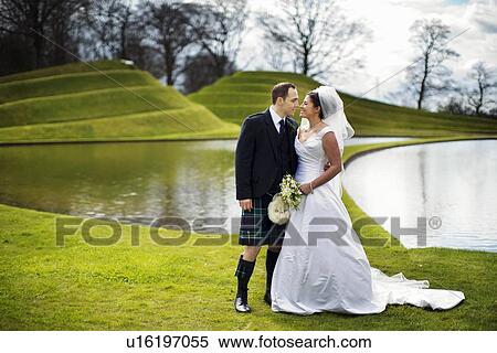 Newlywed couple kissing in field View Large Photo Image Stock Photography - Newlywed couple kissing in field. Fotosearch