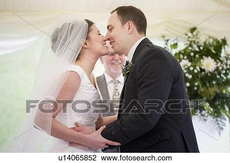 Stock Image - Newlywed couple kissing in wedding. Fotosearch