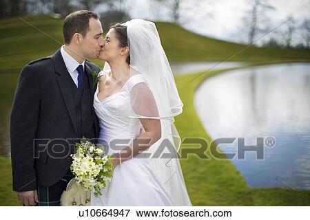 Newlywed couple kissing outdoors View Large Photo Image Stock Photo - Newlywed couple kissing outdoors. Fotosearch