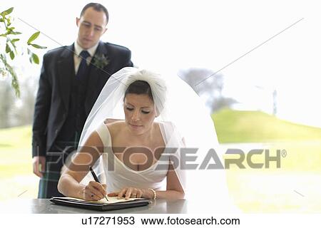 Stock Image - Newlywed couple signing marriage license. Fotosearch