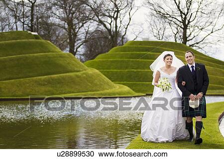 Newlywed couple walking on grassy bridge View Large Photo Image Stock Image - Newlywed couple walking on grassy bridge. Fotosearch