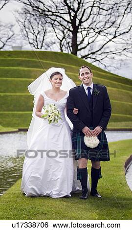 Stock Photograph - Newlywed couple walking on grassy bridge. Fotosearch