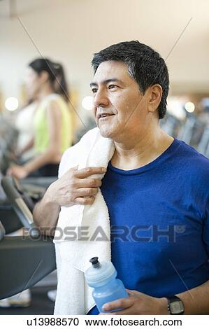 Stock Image - Older man toweling off in gym. Fotosearch