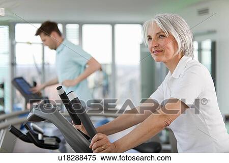 Stock Photography - Older woman using treadmill in gym. Fotosearch