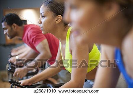 Stock Image - People using spin machines in gym. Fotosearch