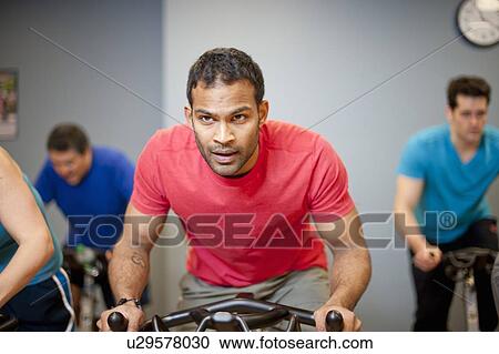 Stock Image - People using spin machines in gym. Fotosearch