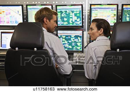 Stock Image - People working in security control room. Fotosearch