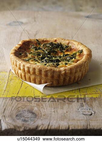 Stock Photo - Quiche in paper on wooden table. Fotosearch