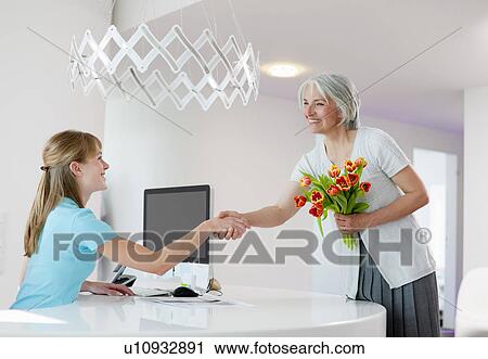 Stock Image - Receptionist shaking womans hand. Fotosearch