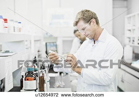 Stock Image - Scientist examining liquid in lab. Fotosearch