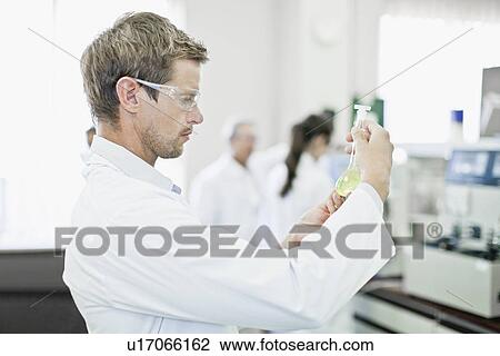 Stock Image - Scientist examining liquid in lab. Fotosearch